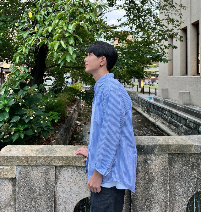 緑のある街並みで横顔を捉えた、自然な他撮り風のサブ写真