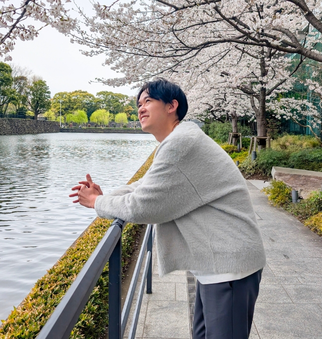 桜と水辺を背景に、穏やかで親しみやすい雰囲気が伝わる写真
