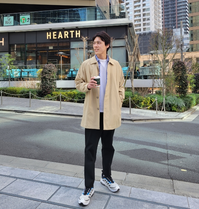街中で飲み物を持つ自然な立ち姿を収めた、友達に撮られたような写真